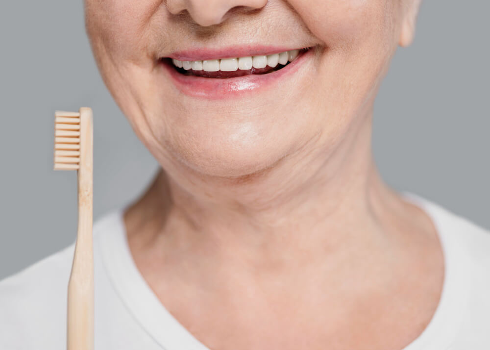 close-up shot of a woman's smile while holding up a wooden toothbrush