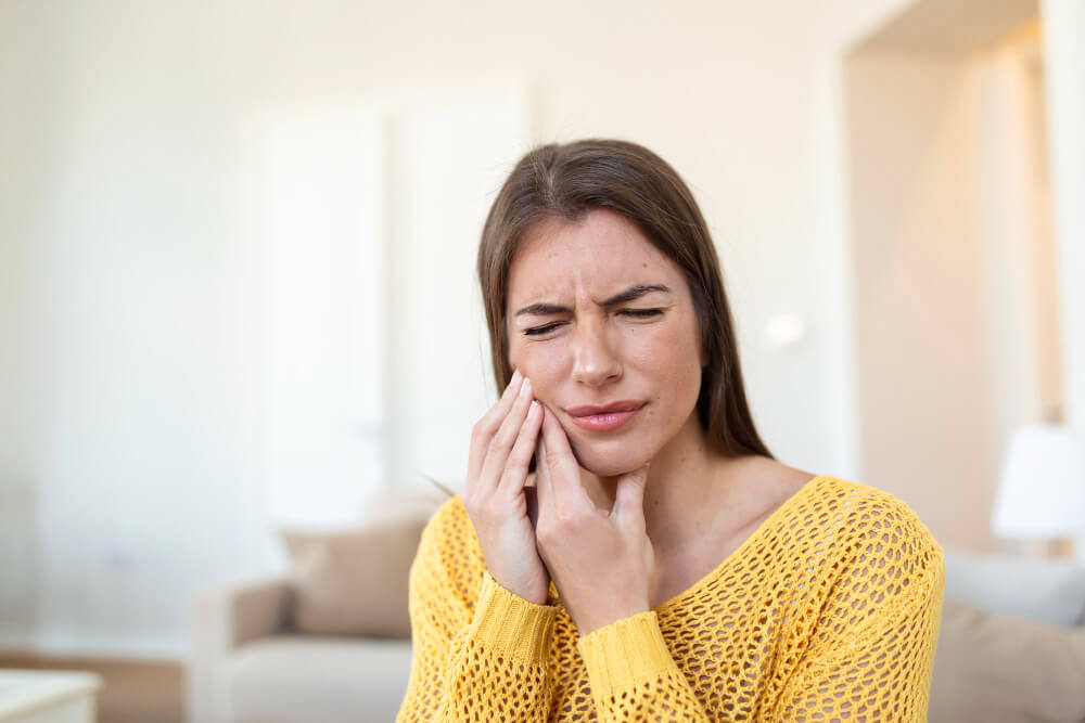 a woman pressing her jaw due to sensitivity